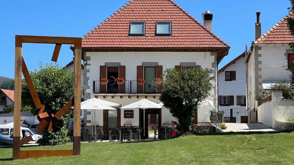 Un grand bâtiment blanc avec un balcon et des parasols est disponible. dans l'établissement HOTEL RURAL BASQUE IRATI, à Espinal-Auzperri