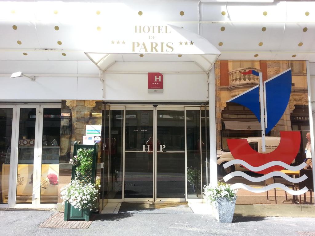ルルドにあるHôtel de Parisの赤い椅子を前に置いた建物の店舗