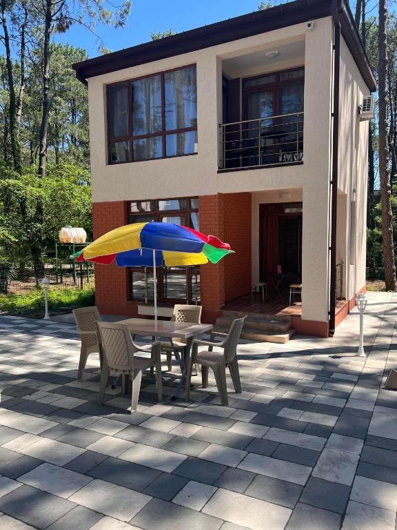 a table with chairs and an umbrella in front of a house at Villa Premium Shekvetili in Shekhvetili