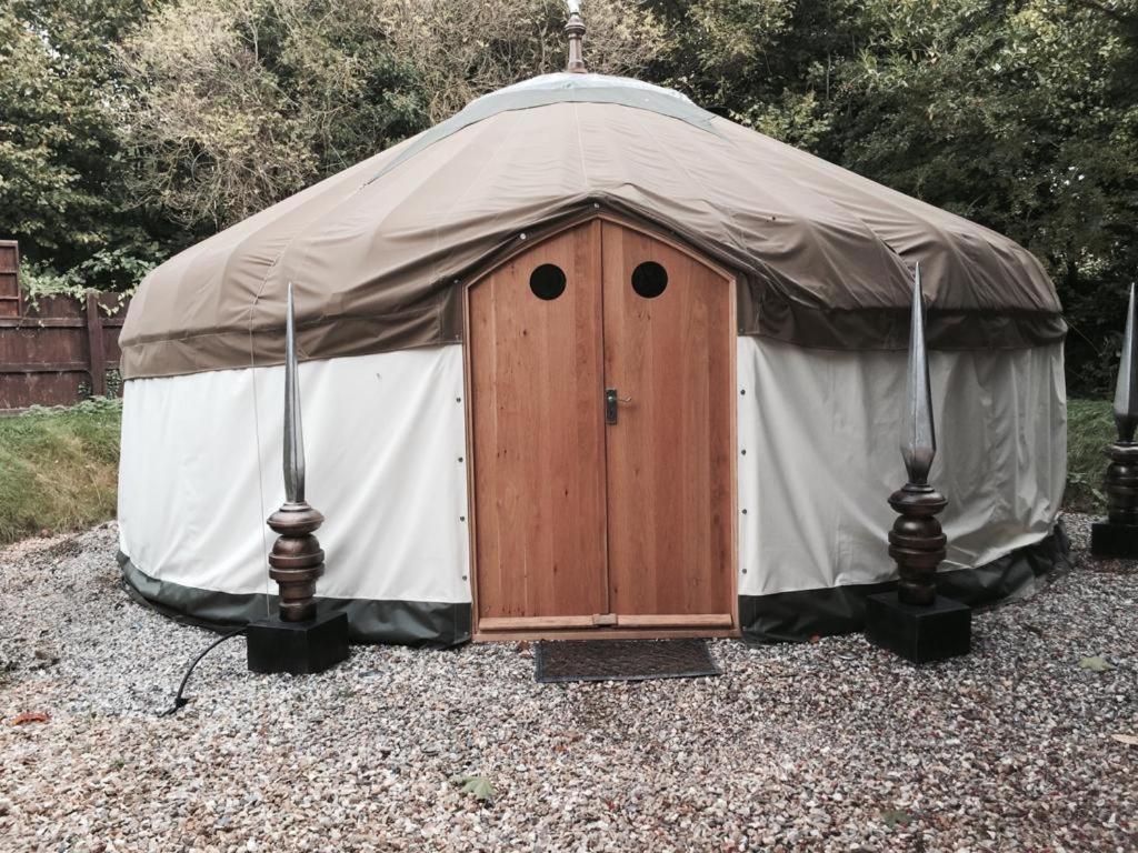 a yurt with a wooden door in a yard at Elodie Yurt in Bishopsteignton