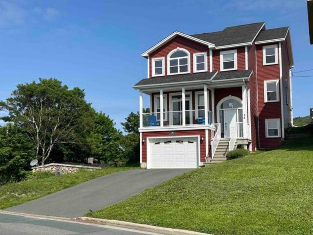 a red house with a garage on a driveway at Experience Coastal Charm-The Vista At Quidi Vidi! in St. John's