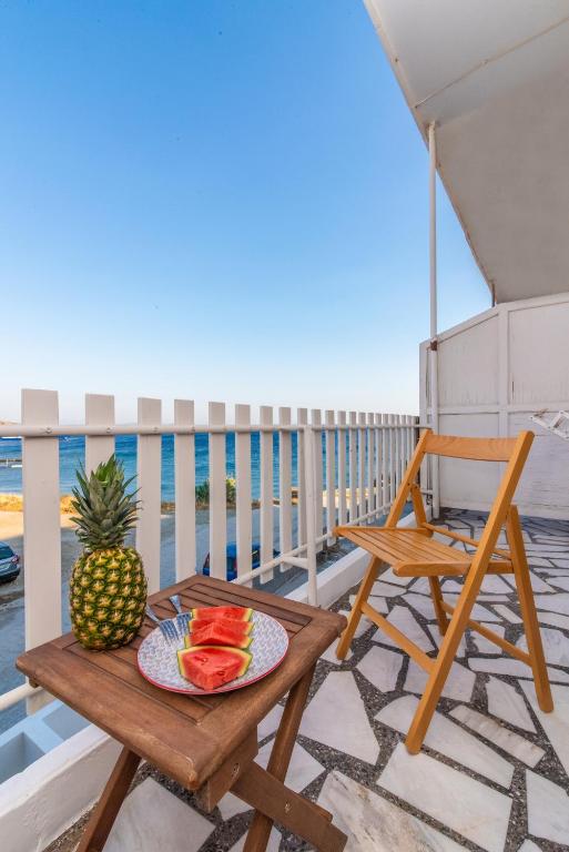 a table and a chair on a balcony with a plate of fruit at Escape in Tinos in Tinos