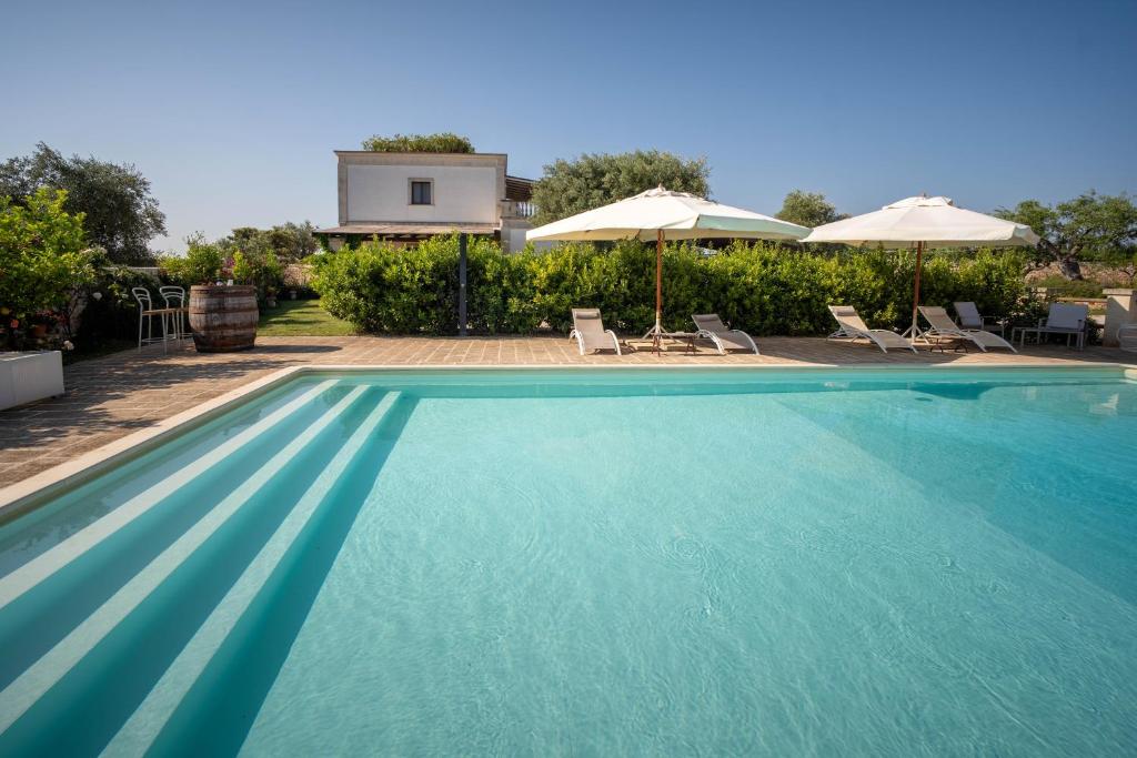 a large swimming pool with chairs and umbrellas at TERRA TERRA - Masseria Minunni in Conversano