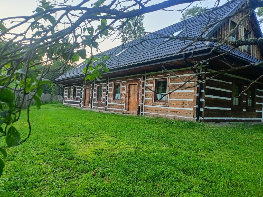 a log cabin with a grass yard in front of it at Zagroda Miodowa agroturystyka w Bieszczadach in Komańcza