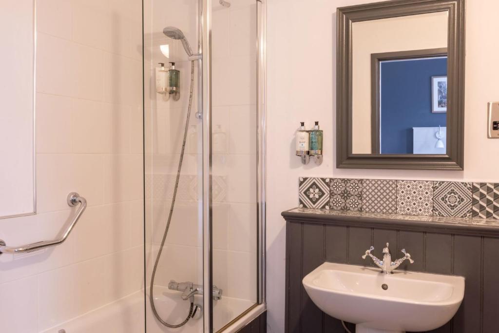a bathroom with a shower and a sink and a mirror at The Harrogate Inn - The Inn Collection Group in Harrogate