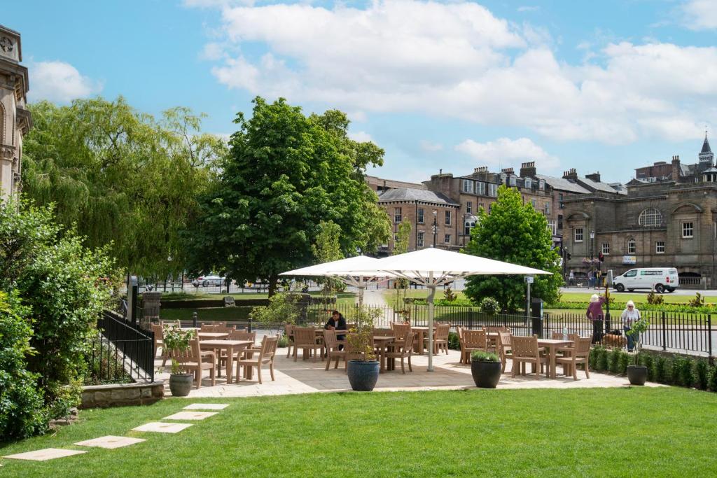 a patio with tables and umbrellas in a park at The Harrogate Inn - The Inn Collection Group in Harrogate