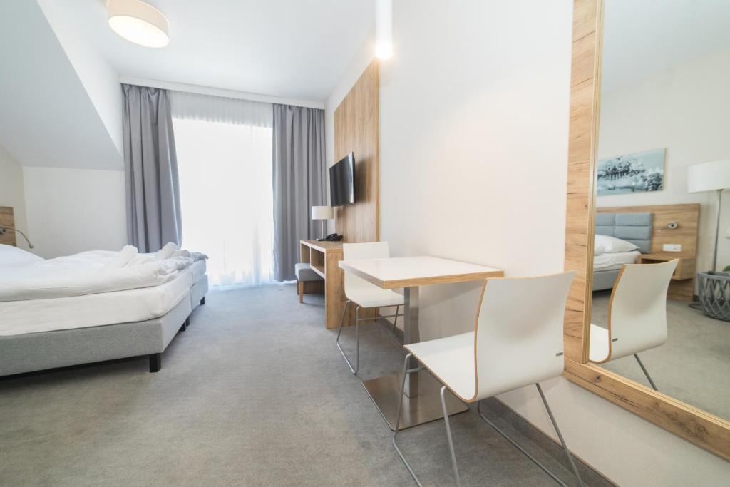 um quarto de hotel com uma cama, uma secretária e um espelho em VacationClub - Aparthotel Czarna Góra 309 em Sienna