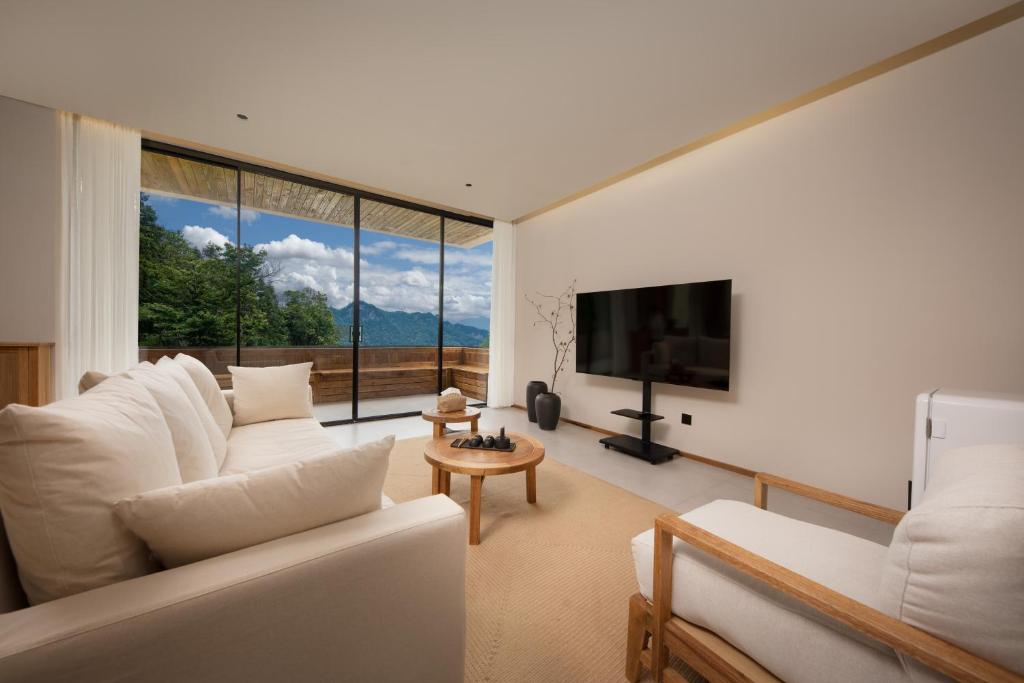a living room with a white couch and a large window at ANNICA Villa in Zhangjiajie