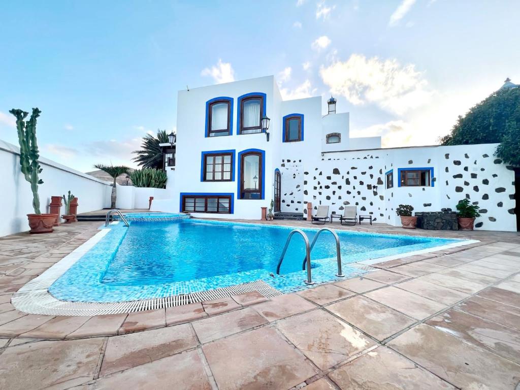 a villa with a swimming pool in front of a house at Doble clásica con desayuno, Wifi y hermosa piscina en Yaiza in Yaiza