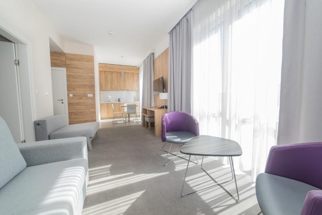 un soggiorno con tavolo e sedie viola di VacationClub - Aparthotel Czarna Góra 221 a Sienna