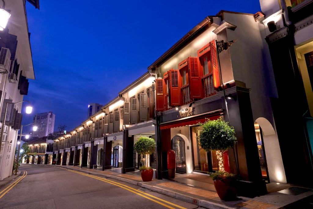 uma rua com uma fila de edifícios à noite em The Scarlet Singapore em Singapura