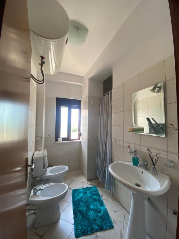 bagno con 2 servizi igienici, lavandino e specchio di Panoramic apartment a Shkodër