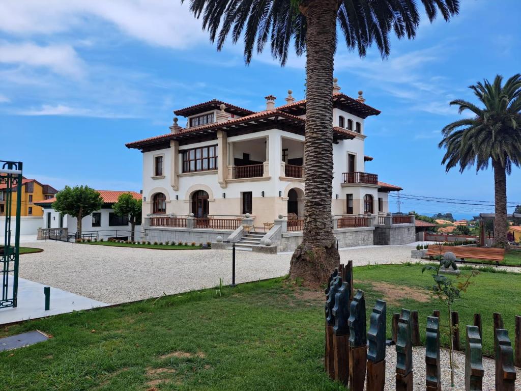 uma casa com uma palmeira e uma cerca em Hotel El Rosal de Cudillero em Cudillero