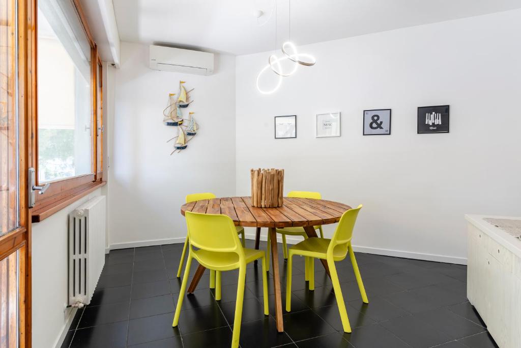 une salle à manger avec une table en bois et des chaises jaunes dans l'établissement Livorno Sea View Flat W/ Balconies near the Beach!, à Livourne