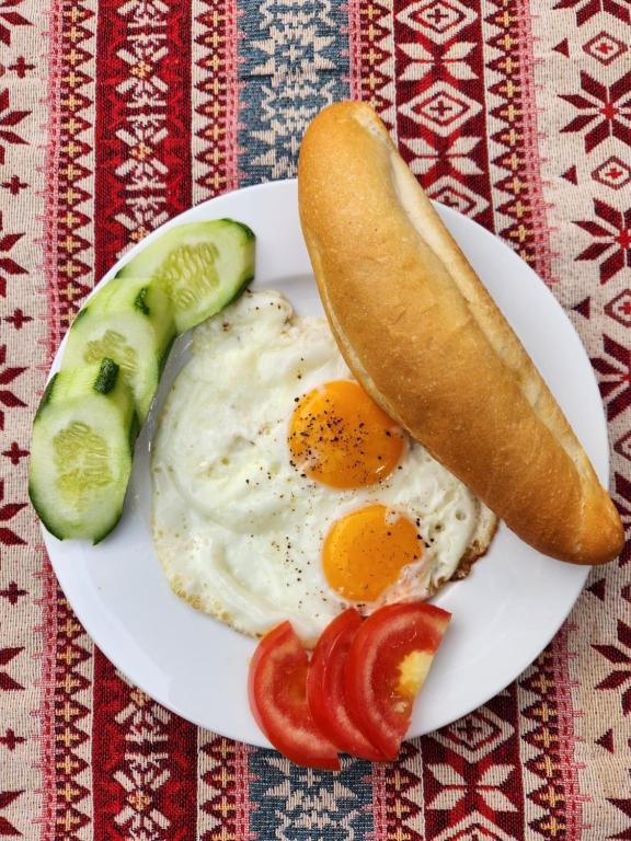 a plate with eggs and a hot dog and a pickle at Catba Papillon Garden Bungalows & Resort in Cat Ba