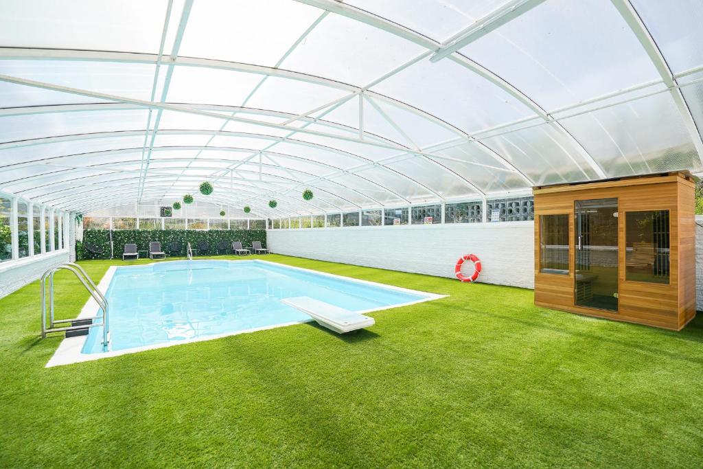 an indoor swimming pool with a glass roof at Spa home with pool sauna hottub & cocktail bar in Sheffield