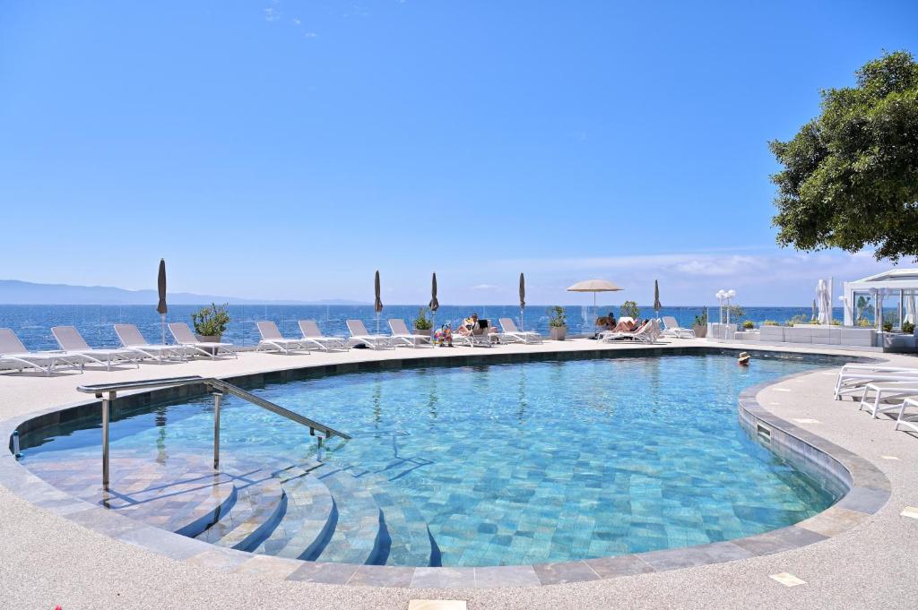 een groot zwembad met ligstoelen en de oceaan bij Hôtel Restaurant Dolce Vita in Ajaccio