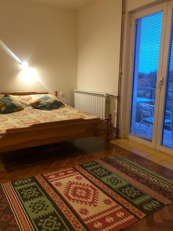 a bedroom with two beds and a window and two rugs at Apartments Zlatiborski visovi in Zlatibor