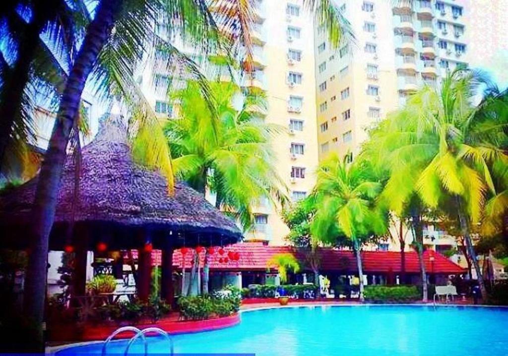 a swimming pool with palm trees and a building at Malacca Hotel Apartment in Melaka
