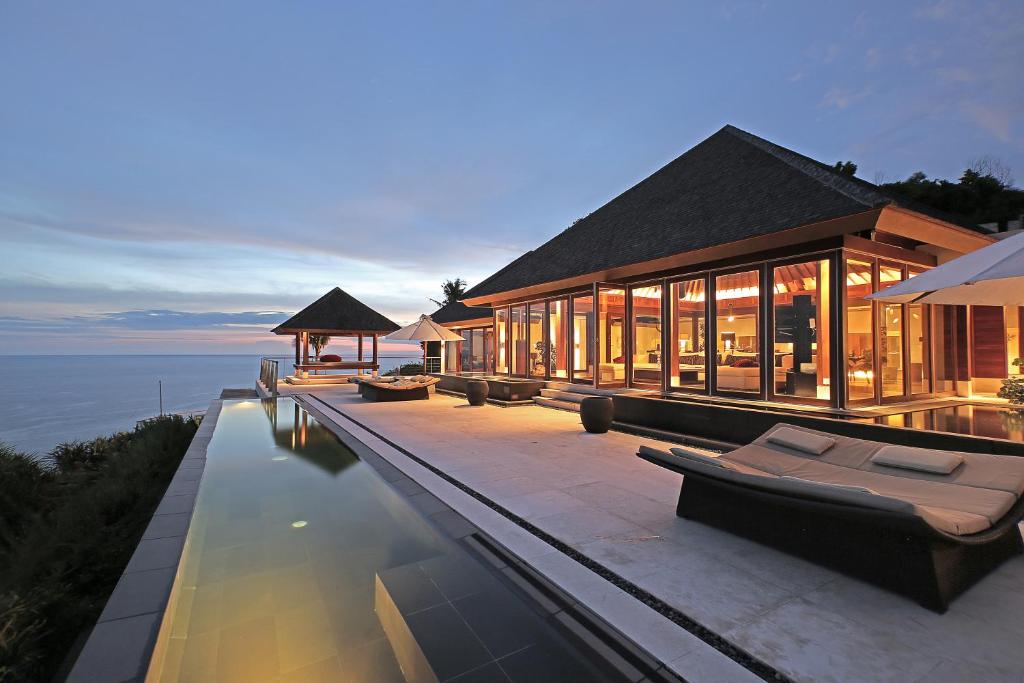 a house with a swimming pool next to the water at The Edge Bali in Uluwatu