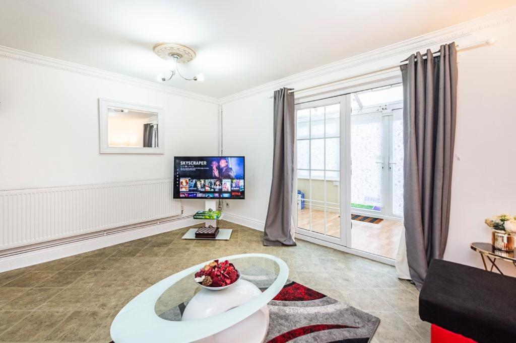 Elite 2 Bedroom House in Chadwell Heath/ Romford with Free Wifi and Parking upto 4 guests في Goodmayes: غرفة معيشة مع طاولة وتلفزيون