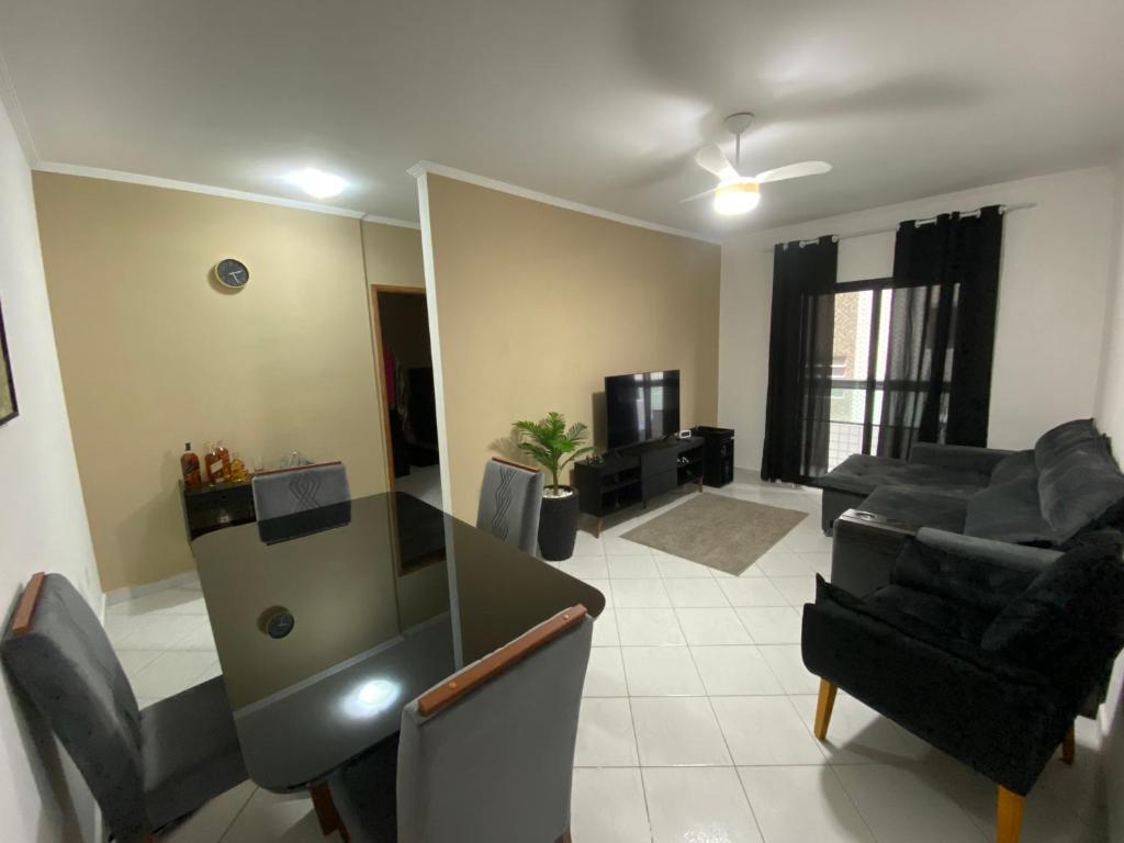 ein Wohnzimmer mit Sofa und Tisch in der Unterkunft Apto Moderno com Churrasqueira Gourmet, apenas 150m da Praia in Praia Grande