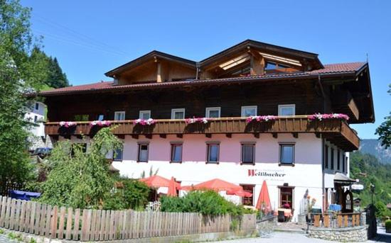 ein großes Gebäude mit einem Holzzaun davor in der Unterkunft Traditionsgasthof Weißbacher in Auffach