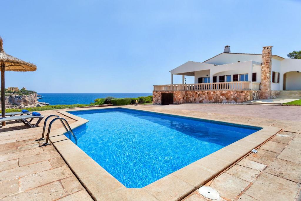 a villa with a swimming pool and the ocean at Can Ferrando de Es Pontas in Cala Santanyi