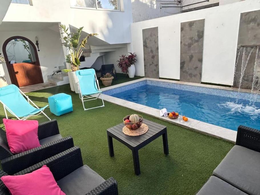 - un salon avec une piscine, des chaises et une table dans l'établissement Villa du Bey à La Marsa, à La Marsa
