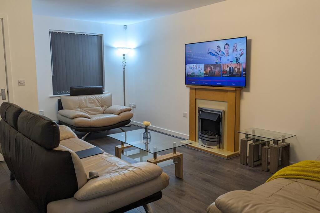a living room with couches and a flat screen tv at ClariTurf - 4 Bedroom Semi - Private Parking near Turf Moor, Town Centre, Transport and Motorway Links next to Canal, 3 Parks and Lake - Sky and Netflix in Burnley