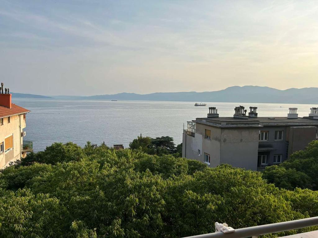 Blick auf das Wasser und ein Gebäude mit Bäumen in der Unterkunft Sea Touch Apartment in Rijeka