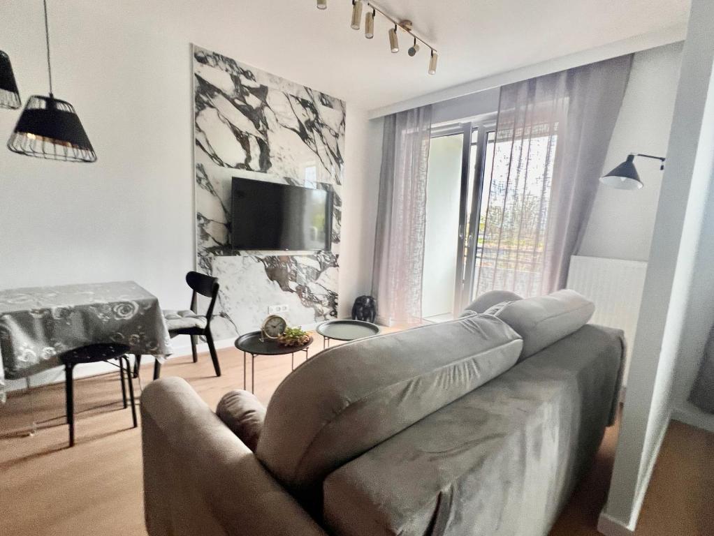 a living room with a couch and a table at Gold Sleep nowy apartament z jacuzzi na wyłączność in Wrocław