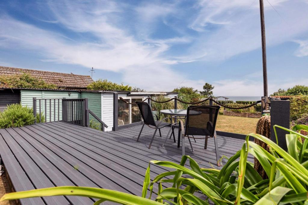 a wooden deck with chairs and a table on it at Seaview in Mundesley