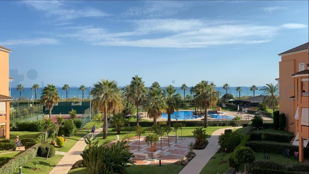 Blick auf einen Park mit Palmen und einem Pool in der Unterkunft Las Terrazas Islantilla in Huelva