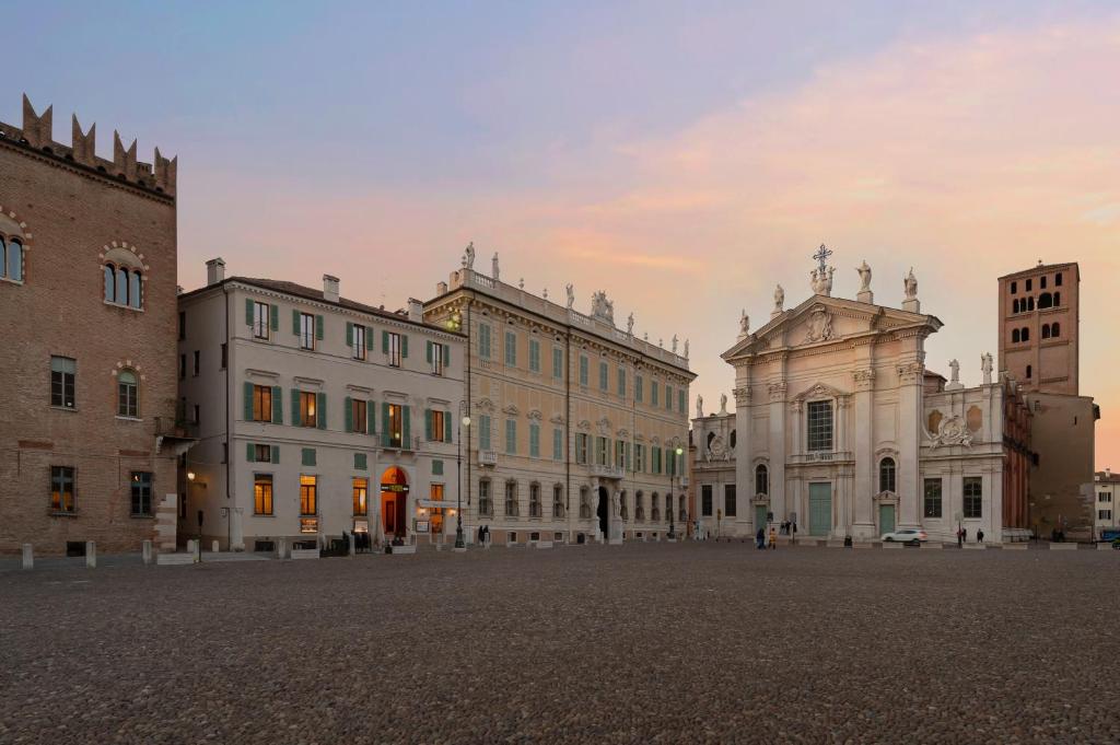 um grupo de edifícios numa praça com o pôr-do-sol em Cà Uberti Palace Hotel em Mântua