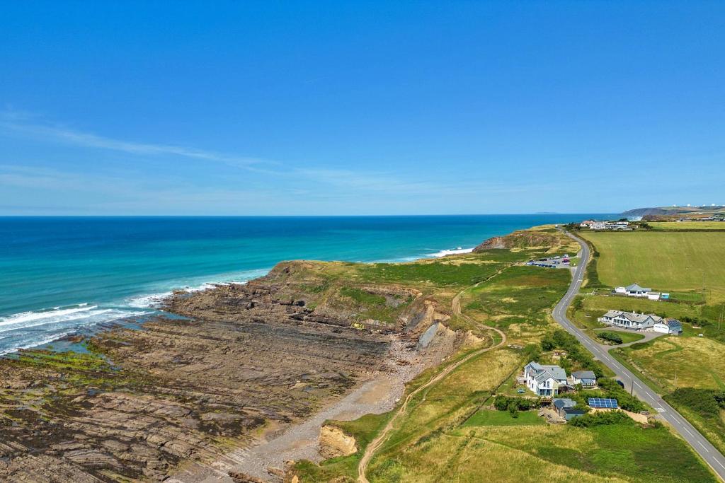 an aerial view of the ocean and houses on a cliff at Finest Retreats - Driftwood in Poundstock