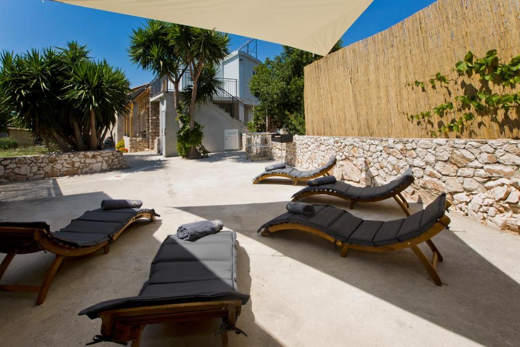 a group of chairs and tables in front of a stone wall at Robinson house T'n'T in Hvar