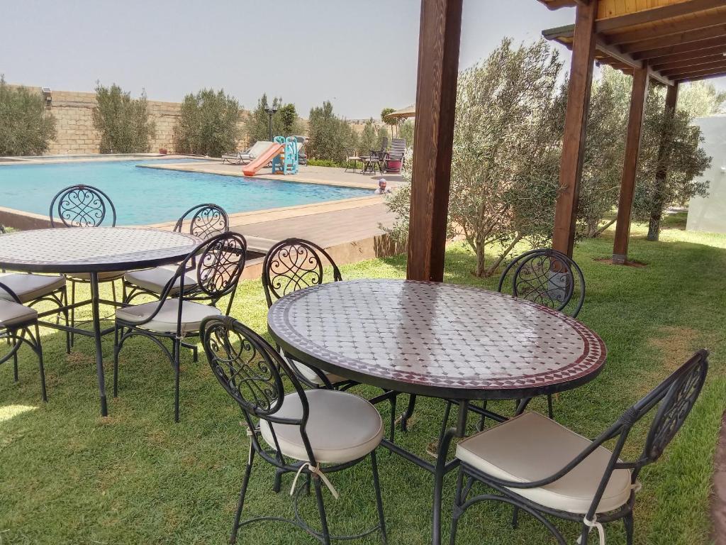a group of tables and chairs next to a pool at Ferme de Rayan in Safi
