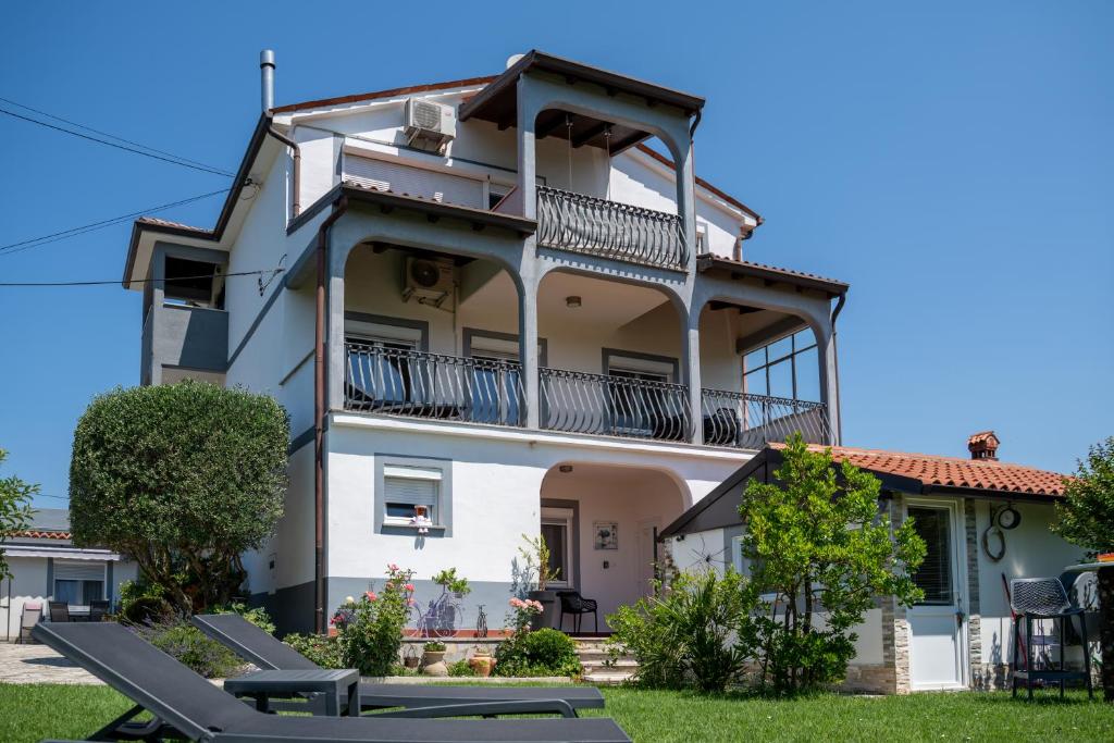 Großes weißes Gebäude mit Balkon in der Unterkunft Apartments Villa Bazilika in Sečovlje