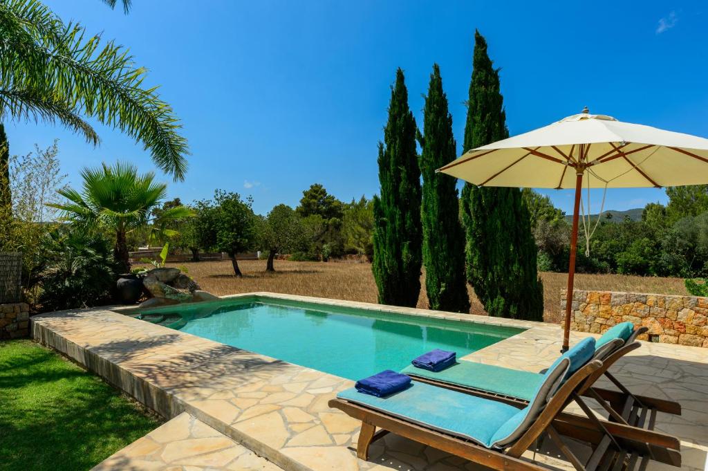 a swimming pool with an umbrella and a chair at Villa Can Curreu in Sant Carles de Peralta