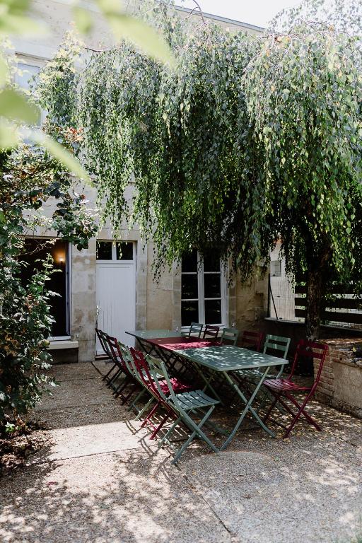 une table et des chaises sous un arbre devant une maison dans l'établissement Maison Madeleine, à La Flèche