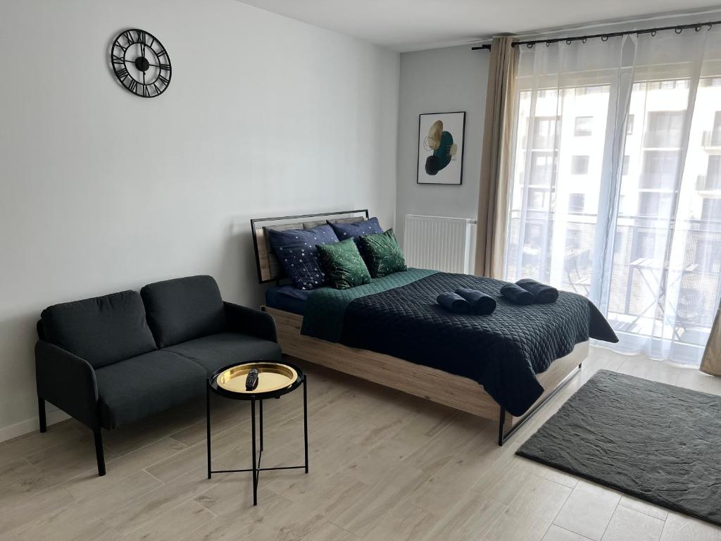 sypialnia z łóżkiem, kanapą i zegarem w obiekcie Harmonia Apartments w Szczecinie