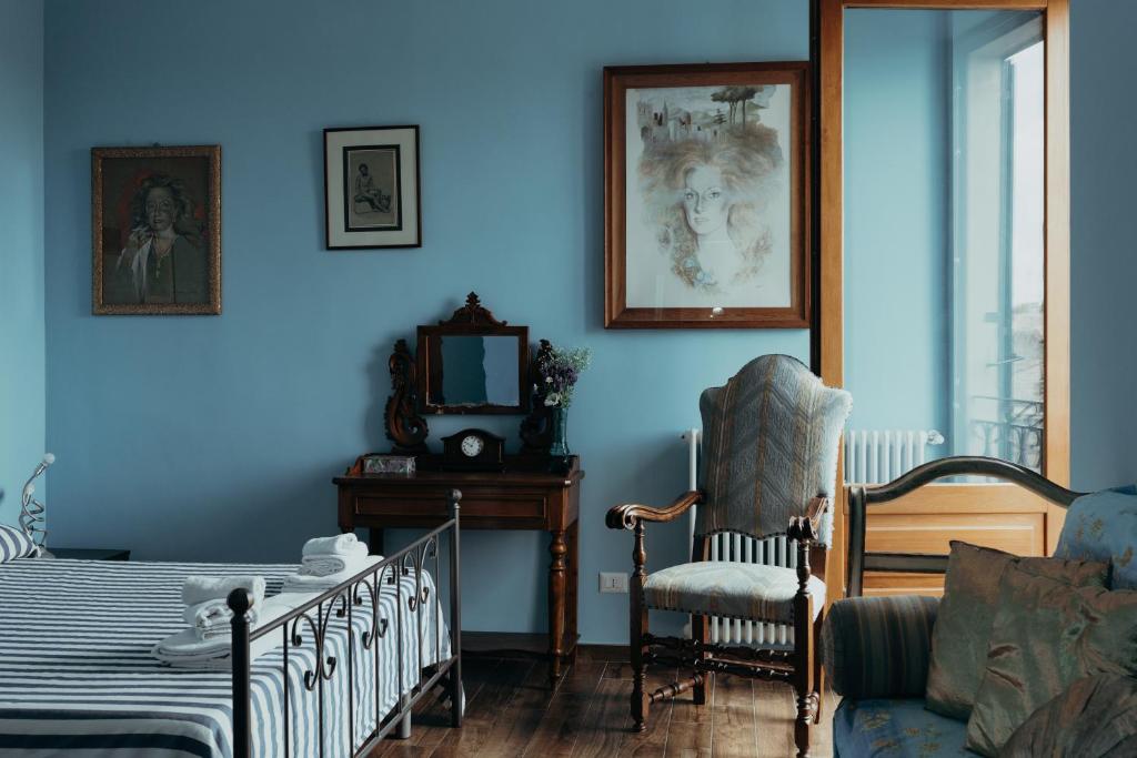 um quarto com paredes azuis e uma cama e uma cadeira em Casa Caracciolo em Pitigliano
