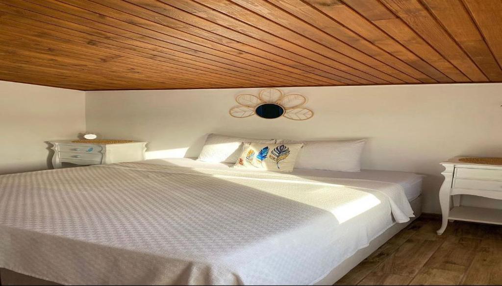 sypialnia z białym łóżkiem i drewnianym sufitem w obiekcie Sığacık Poseidon Boutique Hotel w mieście Seferihisar
