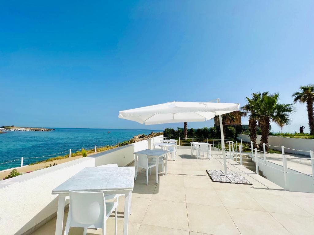un patio con mesas y sombrillas con vistas al océano en Torre Pozzillo Beach en Cinisi