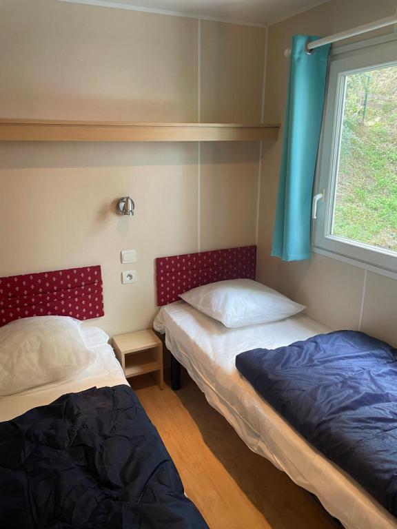 2 camas en una habitación con ventana en Domaine Camping les Roches, en Le Crestet