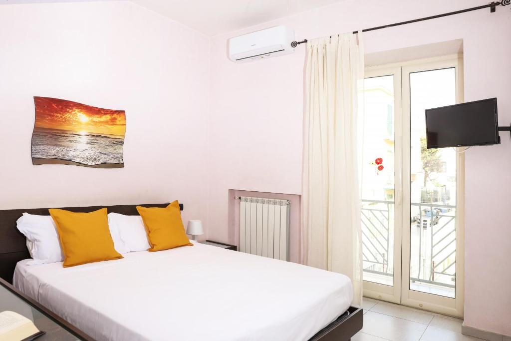 una camera da letto bianca con un letto con cuscini gialli di Metro Solfatara Apartment by Wonderful Italy a Pozzuoli