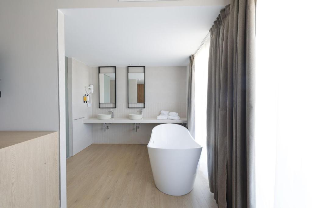 a white bathroom with a sink and a mirror at Hotel H4 Cangas 3 Superior in Cangas de Morrazo