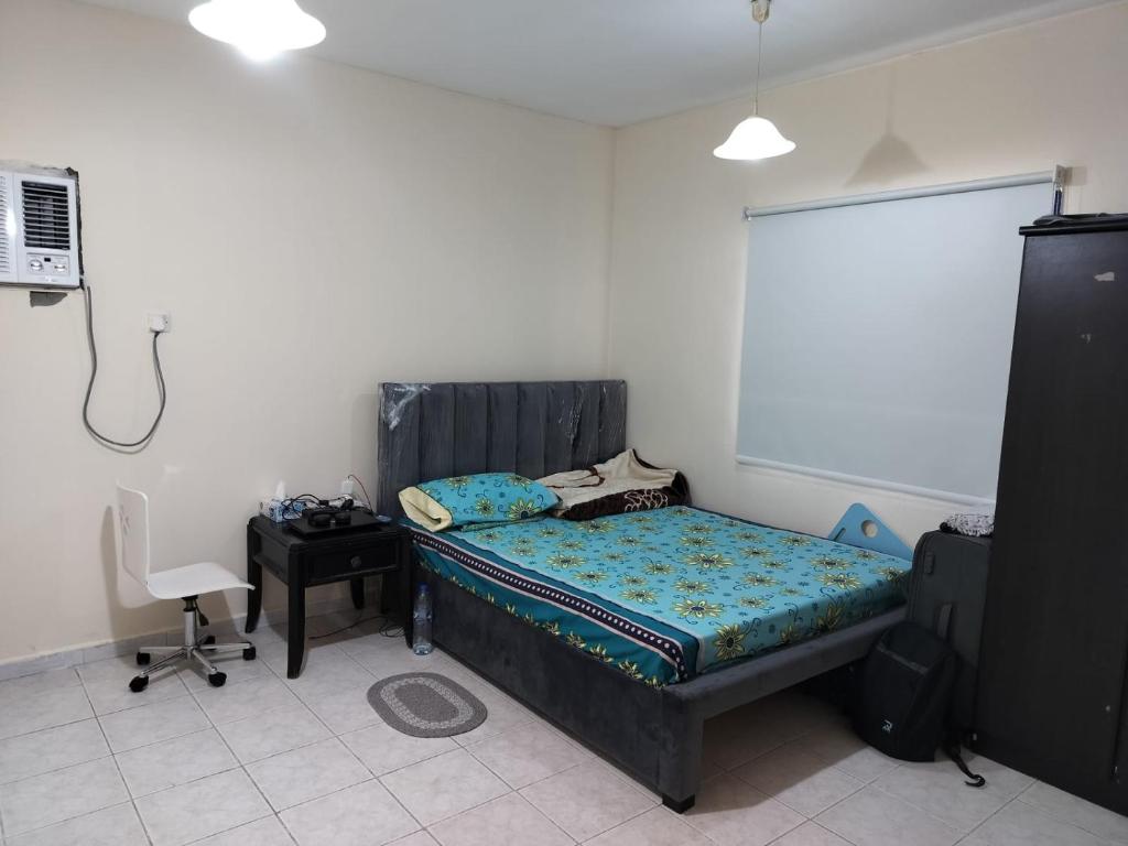 a bedroom with a bed and a desk and a chair at Prem Home Stay in Sharjah