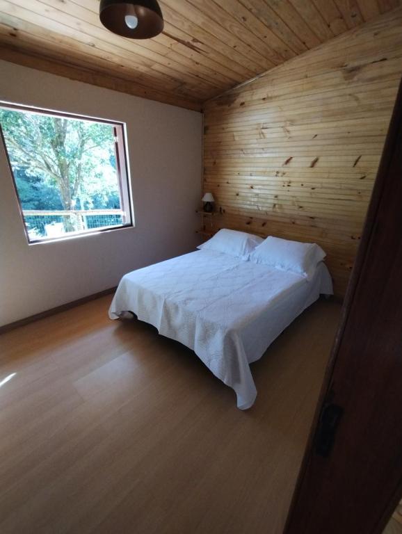 a bedroom with a white bed in a wooden ceiling at Casa Lua in Brumadinho